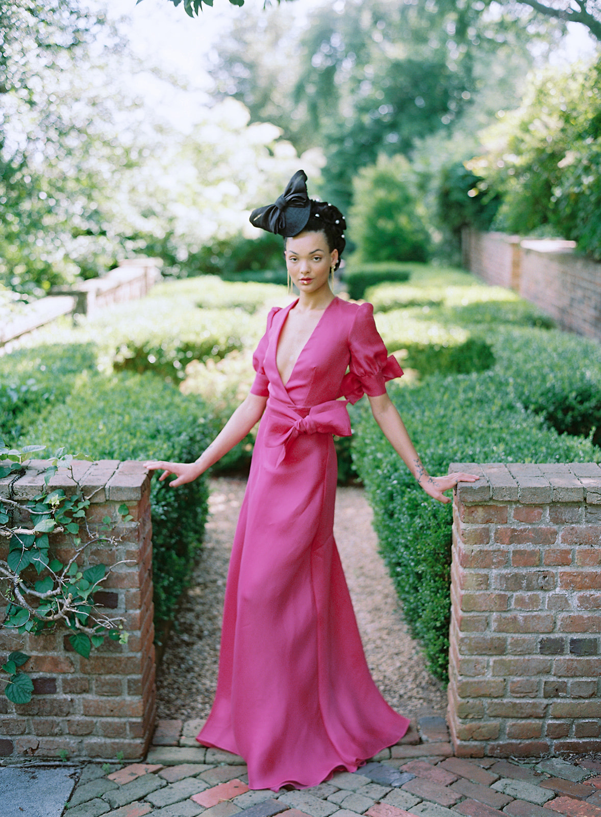 Model in a pink gown with a black hat in an english garden