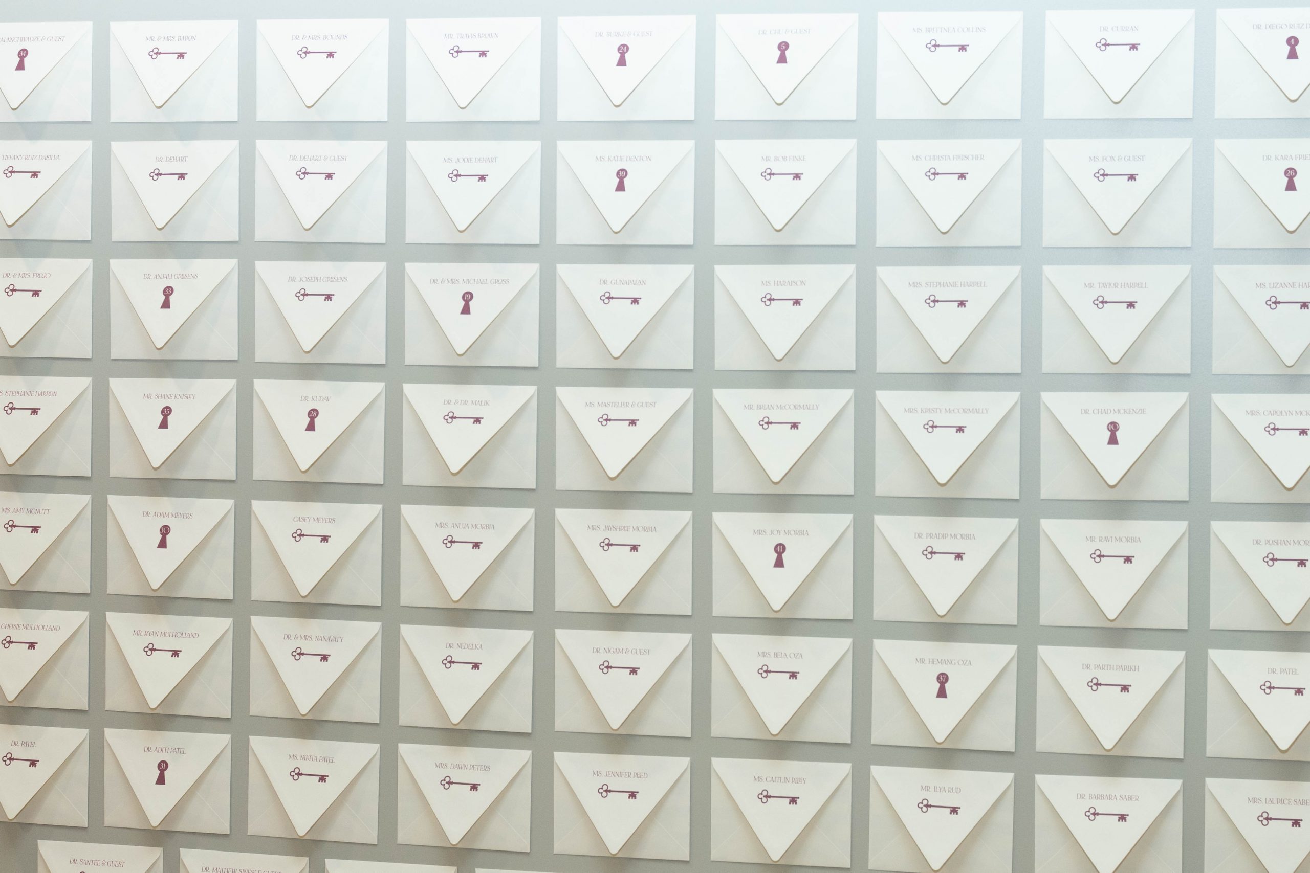 Custom envelope wall installation featuring guest names, table assignments, and hidden experience cards at the Virginia Plastic Surgery grand opening celebration in Virginia Beach, designed and produced by Lustre Theory.
