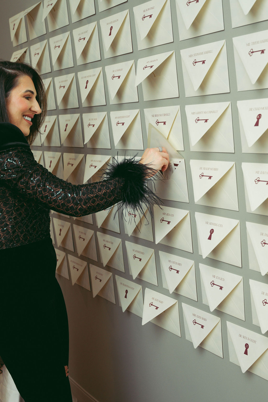 Guest interacting with a custom envelope wall installation featuring personalized invitations and hidden event experiences at a Virginia Beach corporate grand opening event designed by Lustre Theory.